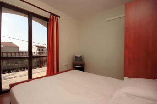 a bedroom with a bed and a window and a television at Studio Duce 4852b in Duće