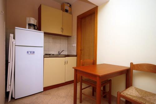 a kitchen with a white refrigerator and a table at Studio Duce 4852b in Duće