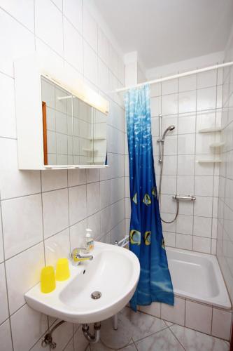 a bathroom with a sink and a blue shower curtain at Double Room Palit 5044b in Rab