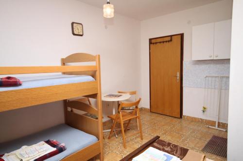 Zimmer mit Etagenbetten, einem Tisch und einer Tür in der Unterkunft Triple Room Povljana 6476b in Povljana