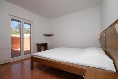 a white bedroom with a bed and a window at Double Room Metajna 6487d in Metajna