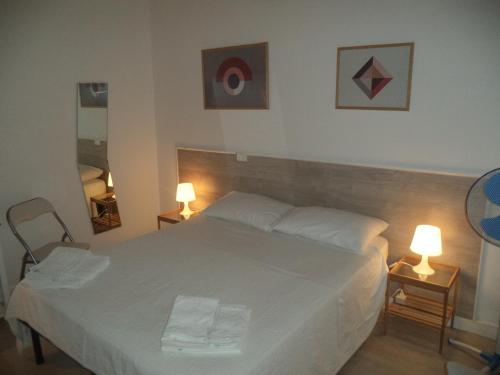 a bedroom with a white bed with two lamps on tables at La Casuzza in Castellammare del Golfo