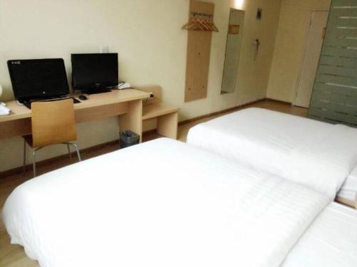 um quarto com duas camas e uma secretária com dois monitores em 7Days Inn Xi'an Northwest University North Gate em Xi'an