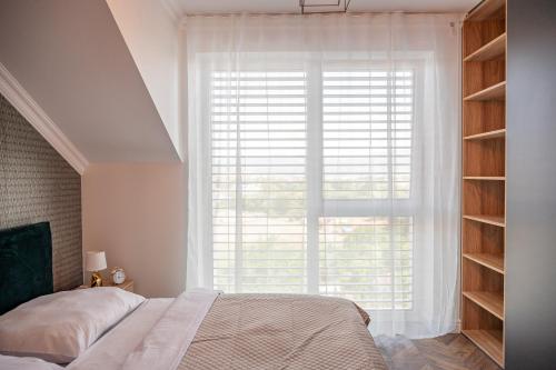 um quarto com uma cama e uma grande janela em Apartmány pod Zámkom em Bojnice