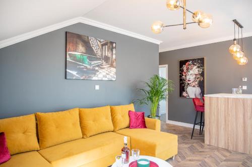 a living room with a yellow couch and a table at Apartmány pod Zámkom in Bojnice