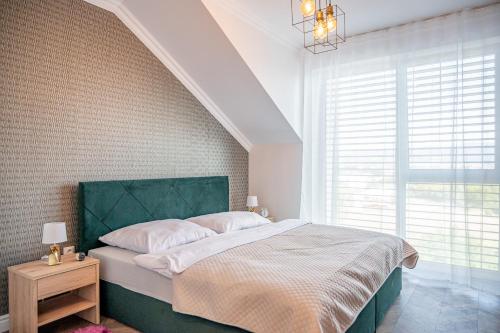 a bedroom with a bed with a green headboard and a window at Apartmány pod Zámkom in Bojnice
