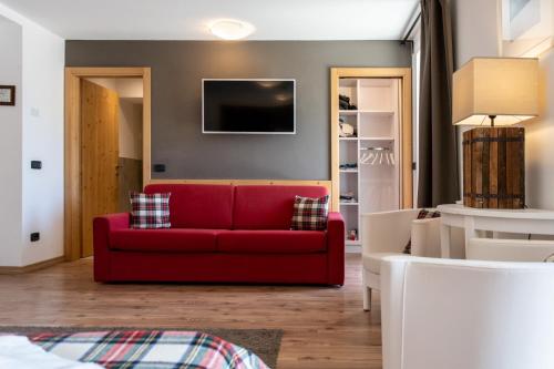 a living room with a red couch and a tv at Ciasa Alpina Relax Hotel in Moena