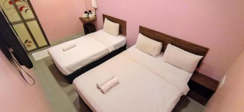 two twin beds in a room with pink walls at Dream House Hotel in Skudai