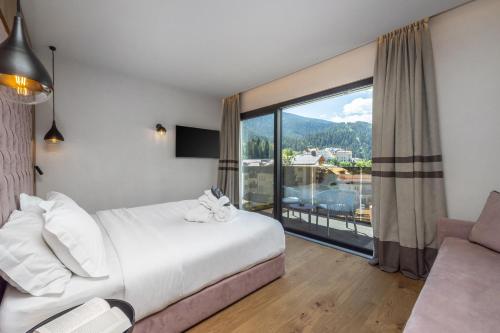 a bedroom with a bed and a large window at Hotel Nordik in Andalo