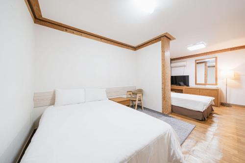 a bedroom with two beds and a desk and a television at Jeju Miracle Hotel in Jeju