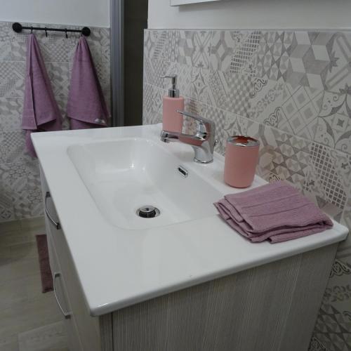 um lavatório branco com uma torneira rosa em Appartamento ROSA - Colori del Lago d'Orta - NUOVA STRUTTURA A OMEGNA em Omegna