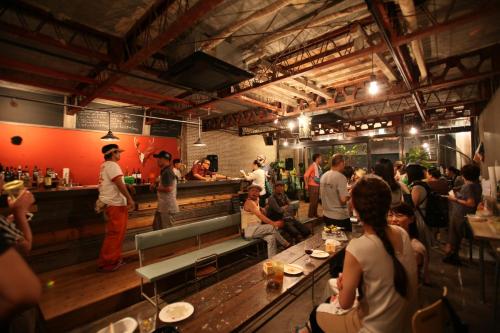 a group of people sitting in a restaurant with a bar at Kamp Houkan-cho Backpacker's Inn & Lounge in Okayama