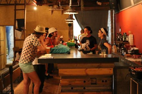 a group of people sitting at a bar at Kamp Houkan-cho Backpacker's Inn & Lounge in Okayama