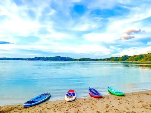 four canoes are lined up on the shore of a lake at Le Grand Bleu in Amami