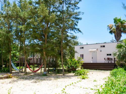 um parque infantil em frente a uma casa com árvores em Le Grand Bleu em Amami