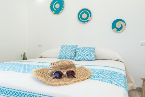 a straw hat and sunglasses sitting on top of a bed at Sa Domm'e Galleria in Baunei