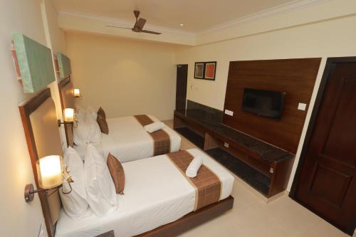 a hotel room with two beds and a flat screen tv at Hotel Comorin Grand in Kanyakumari