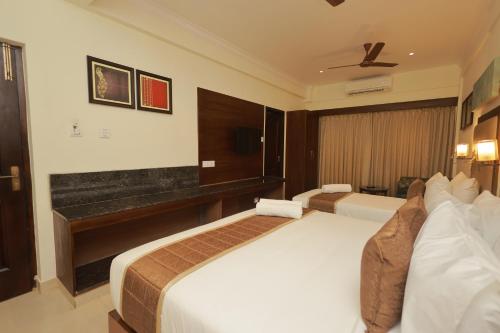 a hotel room with two beds and a piano at Hotel Comorin Grand in Kanyakumari