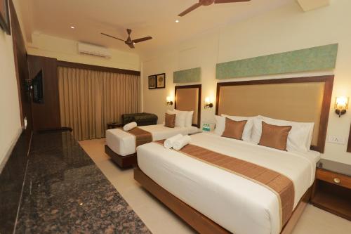 a hotel room with two beds and a chair at Hotel Comorin Grand in Kanyakumari