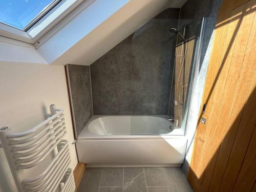 a bath tub in a bathroom with a window at Cuddfan Fach - Pembrokeshire Stunning Barn near the Coastal Path in Abercastle