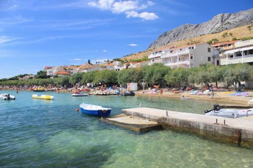 a beach with a group of people and boats in the water at Apartments and rooms by the sea Duce, Omis - 18155 in Omiš