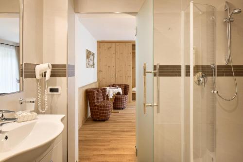 y baño con ducha y lavamanos. en Hotel Comploj Adults only, en Selva di Val Gardena