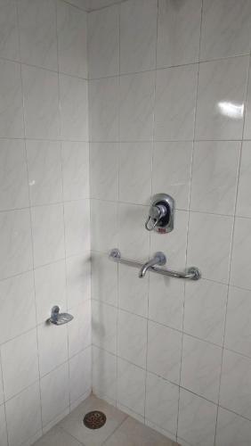 uma casa de banho com um chuveiro com paredes em azulejos brancos em vera home stay em Dehradun