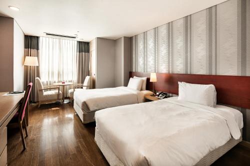 a hotel room with two beds and a desk at Ramada Hotel and Suites Seoul Namdaemun in Seoul