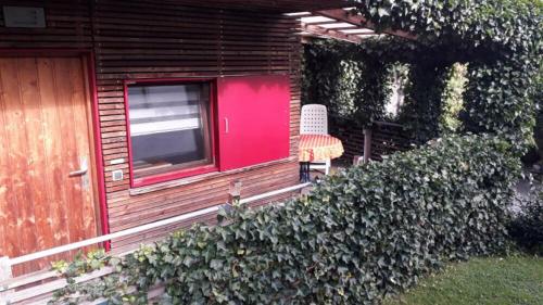 una casa con una puerta roja y una silla en el porche en Ferienhaus am Eichert, en Furth im Wald