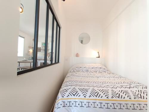 a white bedroom with a bed and a mirror at L'Atelier d'Oscar in Le Havre