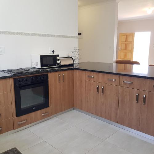 a kitchen with wooden cabinets and a microwave at Entsabeni Cottage in Big Bend