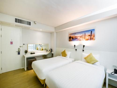 ein Hotelzimmer mit 2 Betten und einem Schreibtisch in der Unterkunft Kitzio House Hotel Huai Kwang in Ban Na Song