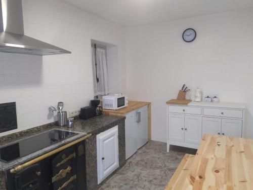 uma cozinha com armários brancos e uma mesa de madeira em Villa Noriega (La Franca) em La Franca