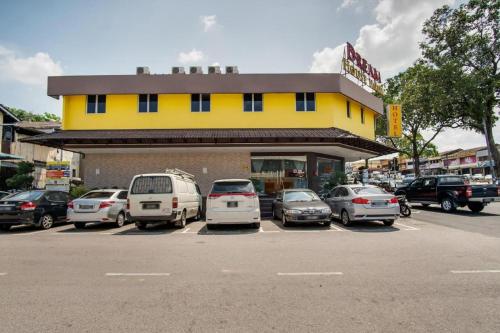 a yellow building with cars parked in a parking lot at Dream House Hotel in Skudai