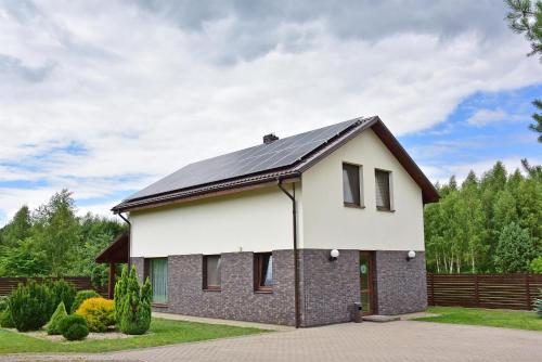 a white house with a black roof at Holiday House Strawberry in Druskininkai