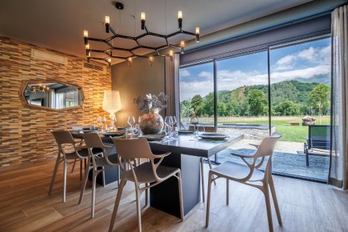 a dining room with a table and chairs and a large window at Pyrénées Prestige - Villas d'exceptions et hébergements insolites in Argelès-Gazost