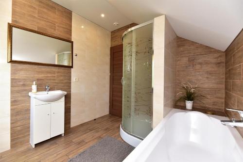 a bathroom with a tub and a sink and a mirror at Holiday House Strawberry in Druskininkai