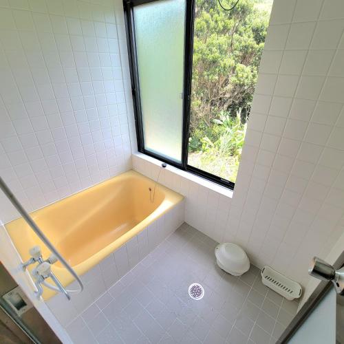 a bathroom with a bath tub and a window at koco in Nishinoomote