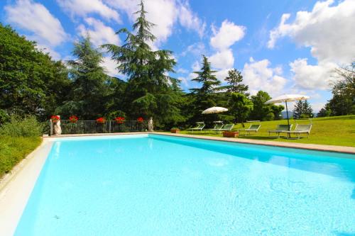a large blue swimming pool with chairs and umbrellas at Villa Cecilia in Castiglion Fiorentino