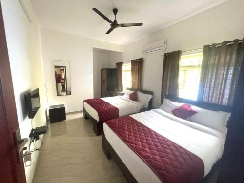 a hotel room with two beds and a ceiling fan at NIDHI RESIDENCY in Guruvāyūr