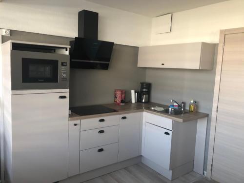 a kitchen with white cabinets and a microwave at Appartement 1 chambre De Haan in De Haan