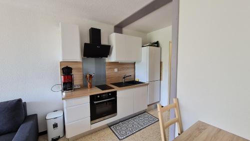 une petite cuisine avec des placards blancs et un canapé bleu dans l'établissement Appartement Cap d'Agde Plage du Mole, au Cap d'Agde