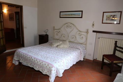 una camera con un letto con una coperta bianca e una sedia di Apartment Piazza Matteotti a Greve in Chianti