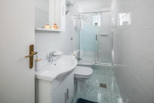 Baño blanco con aseo y lavamanos en Apartments by the sea Zambratija, Umag - 2557, en Zambratija