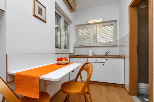 a kitchen with a table and a bowl of fruit on it at Apartments and rooms by the sea Baska Voda, Makarska - 2578 in Baška Voda