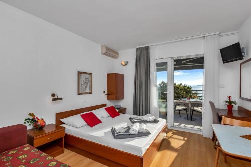 a hotel room with a bed and a balcony at Apartments and rooms by the sea Baska Voda, Makarska - 2578 in Baška Voda