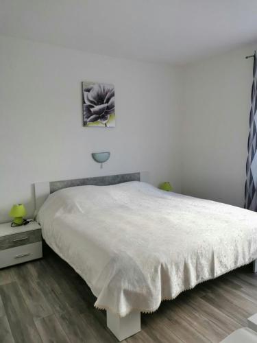 a bedroom with a large white bed and a wooden floor at Apartments with parking space Kampor, Rab - 4985 in Kampor