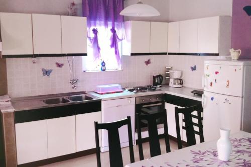 a kitchen with white cabinets and a sink and a stove at Apartments with a parking space Kampor, Rab - 4985 in Kampor