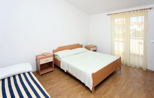 um quarto com uma cama e duas mesas de cabeceira e uma janela em Apartments with WiFi Seget Vranjica, Trogir - 4870 em Trogir