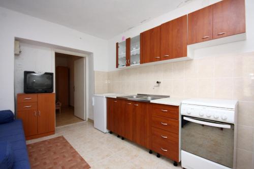 a kitchen with wooden cabinets and a sink and a tv at Apartments with a parking space Sobra, Mljet - 4926 in Babino Polje